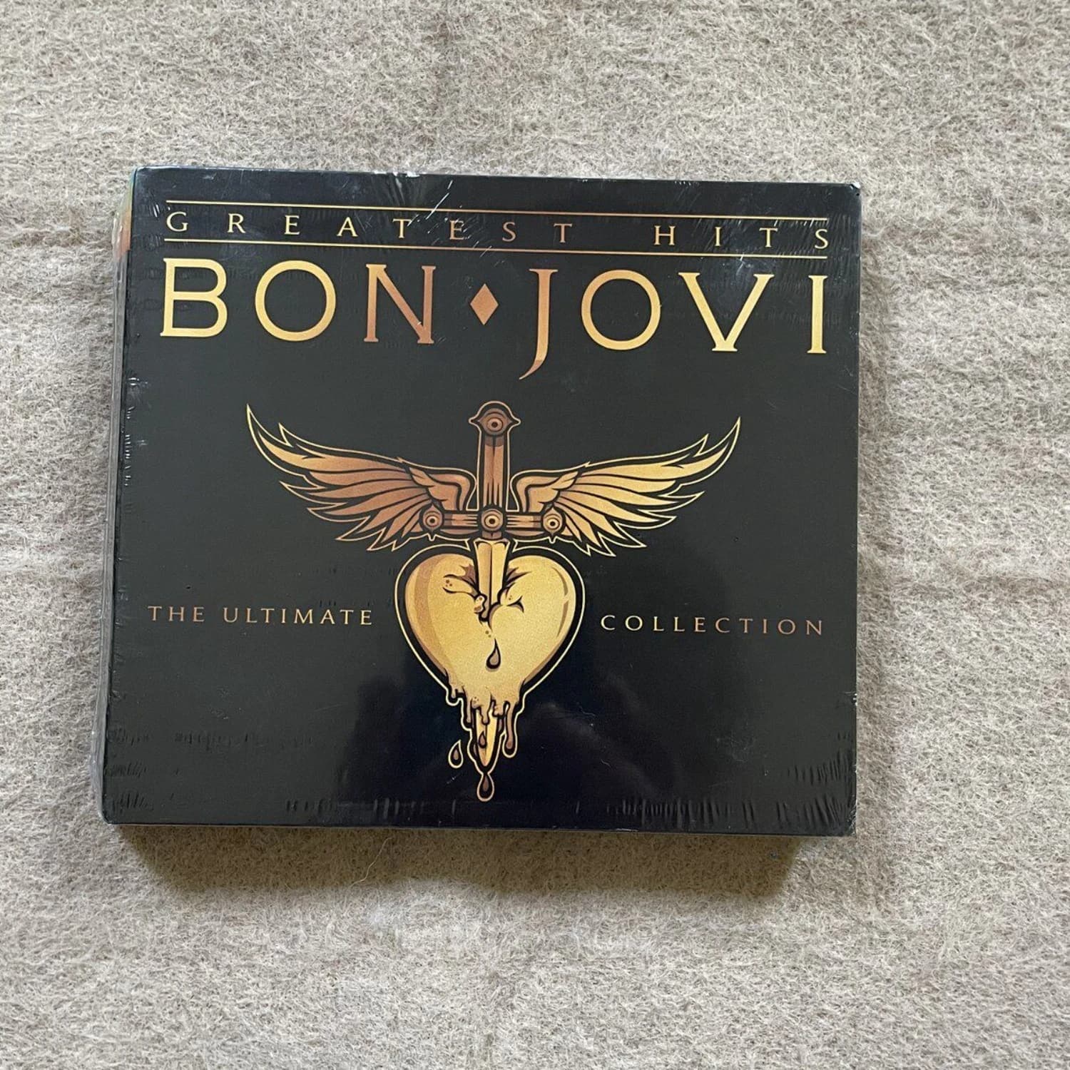 Album CD de musique rock avec couverture artistique audacieuse noire et dorée, logo accrocheur épée-