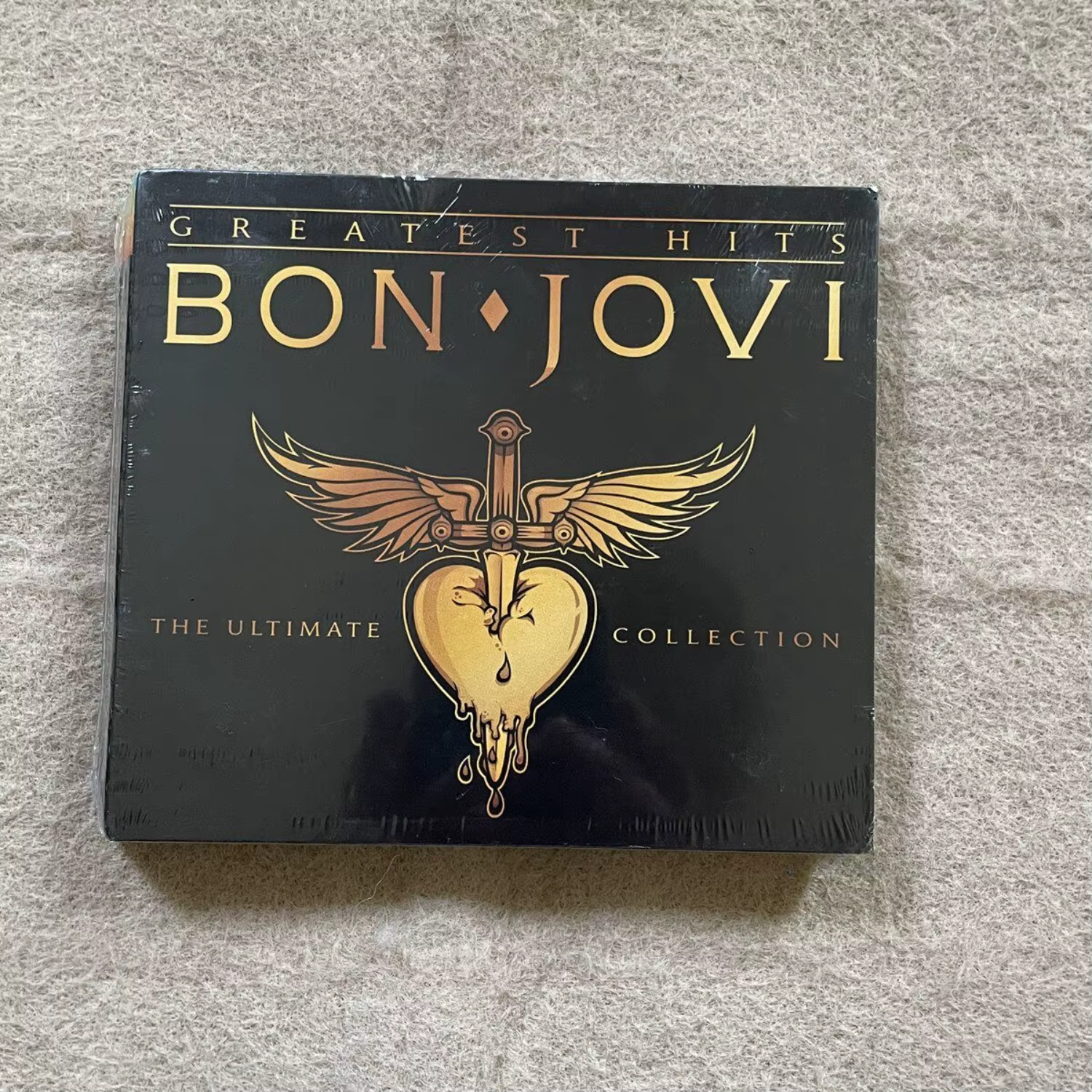 Album CD de musique rock avec couverture artistique audacieuse noire et dorée, logo accrocheur épée-